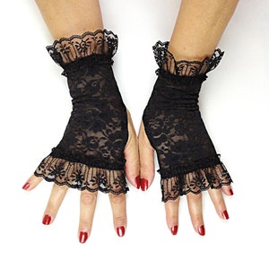 Puede incluir: Un par de guantes sin dedos de encaje negro con ribete de volantes. Los guantes est&aacute;n hechos de una tela transparente y tienen un delicado patr&oacute;n floral.