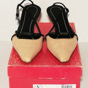 Puede incluir: Un par de zapatos de tac&oacute;n slingback beige y negro con punta fina y tac&oacute;n delgado. Los zapatos tienen un patr&oacute;n texturizado en la parte beige y correas negras. Se muestran sobre una caja roja con texto.