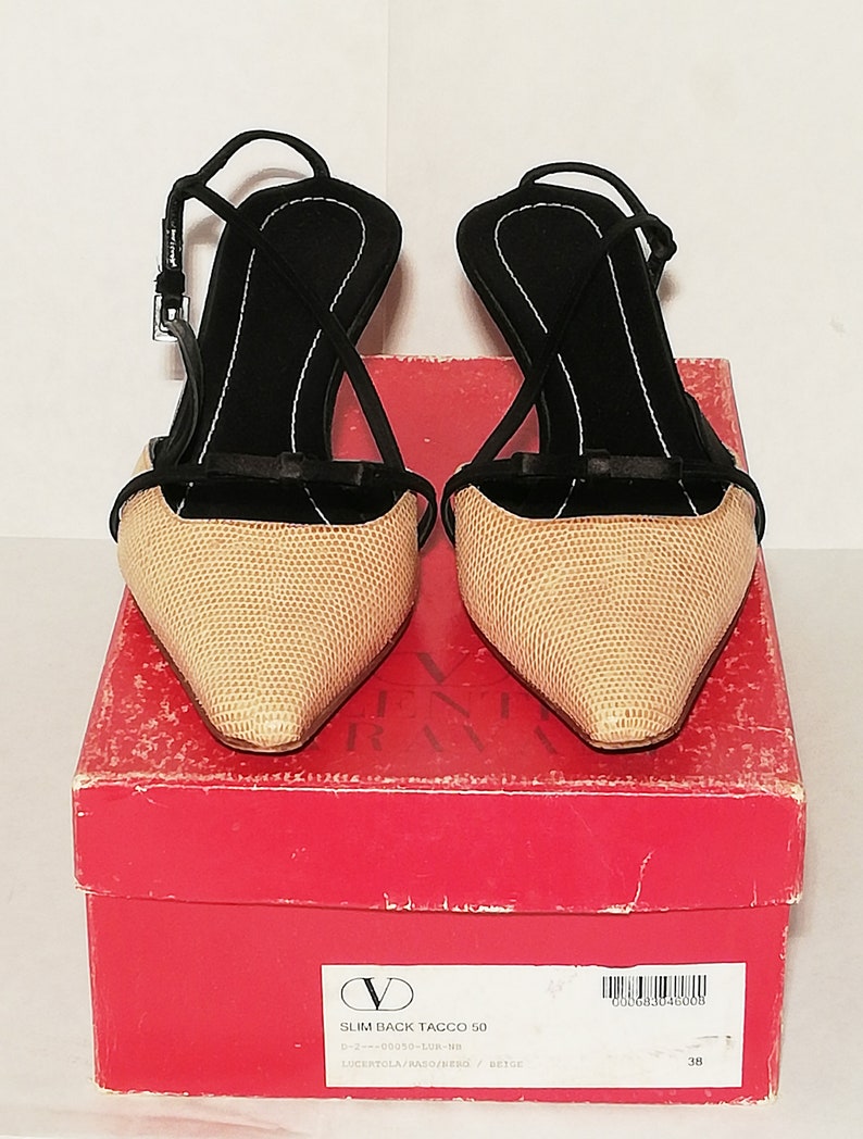 Puede incluir: Un par de zapatos de tac&oacute;n slingback beige y negro con punta fina y tac&oacute;n delgado. Los zapatos tienen un patr&oacute;n texturizado en la parte beige y correas negras. Se muestran sobre una caja roja con texto.
