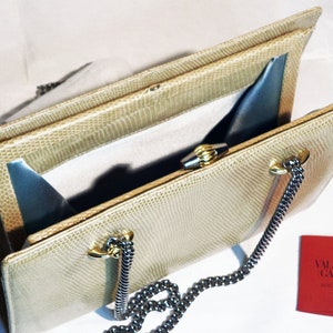Puede incluir: Un bolso de mano de piel de serpiente beige con cierre de broche dorado y correa de cadena. El bolso est&aacute; abierto y el interior est&aacute; forrado con un tejido azul claro. El bolso tiene una etiqueta que dice "Valentino Garavani Made in Italy".