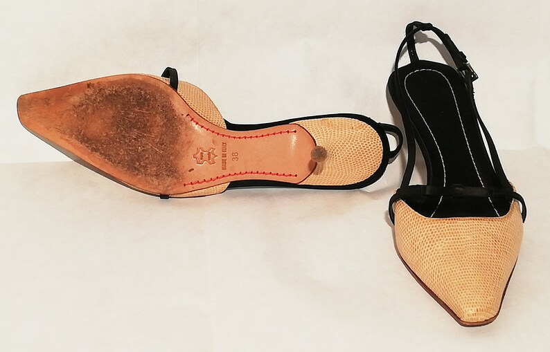Puede incluir: Par de zapatos de tac&oacute;n slingback beige y negro con punta. Los zapatos tienen un patr&oacute;n texturizado en las secciones beige y una correa negra. Las suelas son de cuero con costuras rojas y un tac&oacute;n peque&ntilde;o. Talla 38.