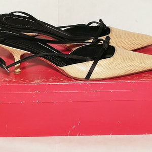 Puede incluir: Un par de zapatos de tac&oacute;n slingback beige y negro con estampado de reptil, sobre una caja roja. Los tacones tienen punta afilada, tiras finas y un tac&oacute;n peque&ntilde;o. Las correas negras se envuelven alrededor del tobillo.
