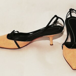 Puede incluir: Un par de zapatos de tac&oacute;n slingback beige y negro. Los zapatos de punta tienen una pala beige texturizada y una correa negra que se envuelve alrededor del tobillo. Los tacones miden aproximadamente 5 cm de alto.