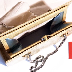 Puede incluir: Un bolso de mano de piel de serpiente beige con una correa de cadena plateada y un cierre dorado. El bolso est&aacute; abierto y el interior est&aacute; forrado con un tejido azul claro. El bolso tiene una etiqueta que dice "V Valentino Garavani Made in Italy."