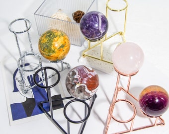 Può includere: Cinque sfere di cristallo di diversi colori su supporti in metallo decorativi. Le sfere sono viola, gialle, rosa, marroni e viola. I supporti sono dorati, argentati e neri.