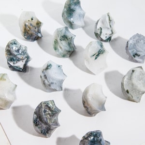 May include: A selection of polished, irregularly shaped stones. The stones are mainly white with green and grey veining, and have a textured, organic appearance. The arrangement suggests a focus on natural elements and decorative objects.