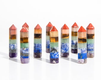 May include: A set of ten chakra crystal wands, each with seven layers of different colored stones. The wands are arranged in a row on a white surface.