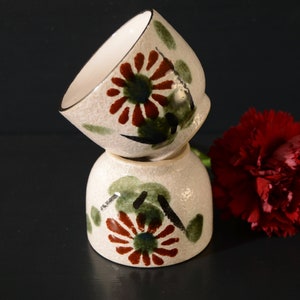 Puede incluir: Dos cuencos de cer&aacute;mica blanca con un dise&ntilde;o floral en tonos verdes, rojos y negros. Los cuencos est&aacute;n apilados uno encima del otro.