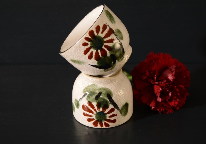 Puede incluir: Dos cuencos de cer&aacute;mica blanca con un dise&ntilde;o floral en tonos verdes, rojos y negros. Los cuencos est&aacute;n apilados uno encima del otro.