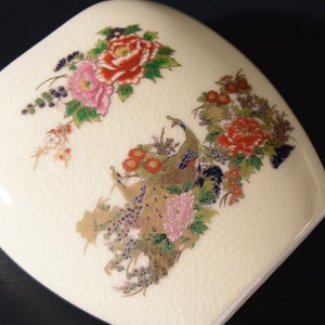 May include: A white ceramic vase with a floral design featuring peacocks, peonies, and other flowers in shades of pink, red, gold, and blue.