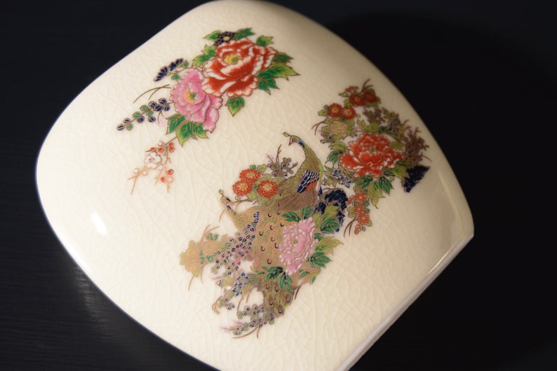 May include: A white ceramic vase with a floral design featuring peacocks, peonies, and other flowers in shades of pink, red, gold, and blue.