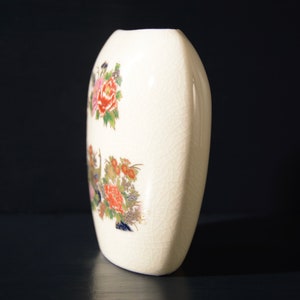 May include: White ceramic vase with a floral design. The vase is oval shaped and has a textured surface.