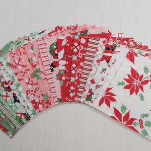 May include: A selection of Christmas-themed fabric squares. The fabrics display red, green, and white patterns, including poinsettias, candy canes, and Santa Claus. The squares are arranged in a fan shape, ideal for quilting.