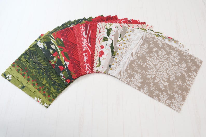 Peut inclure: &Eacute;ventail de carr&eacute;s de tissu assortis dans les tons de vert, rouge, blanc et beige. Les tissus pr&eacute;sentent des motifs floraux et &agrave; motifs, parfaits pour le patchwork ou les projets de couture. Les carr&eacute;s sont dispos&eacute;s en demi-cercle.