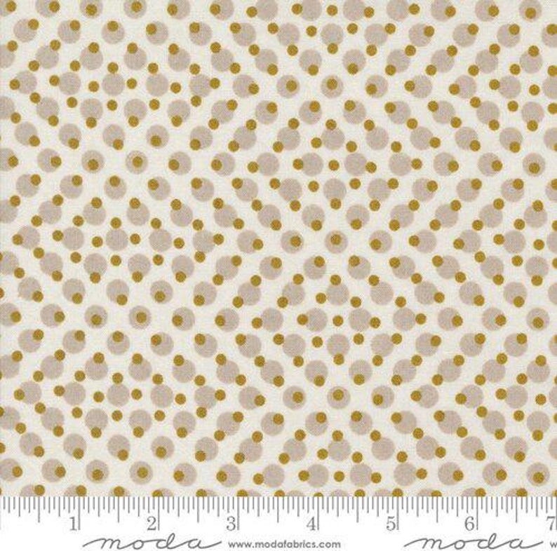 Peut inclure: Tissu cr&egrave;me avec un motif r&eacute;p&eacute;t&eacute; de pois dor&eacute;s et taupe. Les pois sont dispos&eacute;s en diagonale, cr&eacute;ant un aspect textur&eacute;. Une r&egrave;gle en bas indique les mesures en centim&egrave;tres.