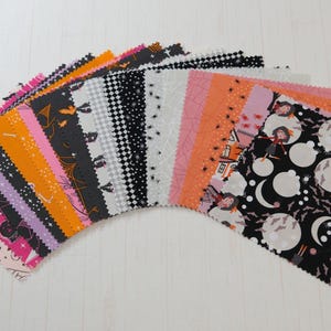 May include: A selection of Halloween-themed fabric squares in various colours and patterns. Designs include bats, witches, moons, and spiderwebs. The fabric pieces are arranged in a fan shape, showcasing the diverse designs.