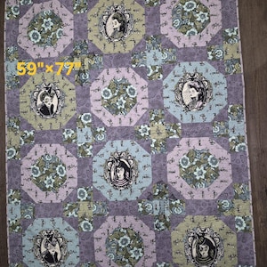 May include: A quilt with a repeating pattern of octagons and squares. The quilt features portraits in ornate frames, floral designs, and a color palette of purple, green, and blue. The quilt measures 150cm x 201cm.