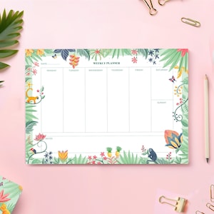 Peut inclure: Un bloc-notes de planification hebdomadaire sur le thème de la jungle tropicale. Le bloc-notes a un fond blanc avec des illustrations florales vertes, roses et jaunes. Les jours de la semaine sont listés en haut : Lundi, Mardi, Mercredi, Jeudi, Vendredi, Samedi et Dimanche. Les mots "Weekly Planner" sont imprimés en noir en haut du bloc-notes.