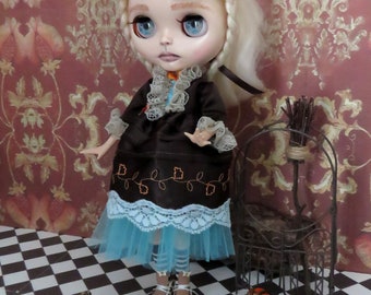 May include: A doll with blonde hair and blue eyes, dressed in a brown dress with a blue skirt and white lace trim. Small orange pumpkins are scattered on a black and white checkered floor. A decorative metal cage is to the right.