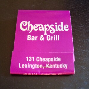 May include: A purple matchbook with white text that reads "Cheapside Bar & Grill" and "131 Cheapside Lexington, Kentucky".