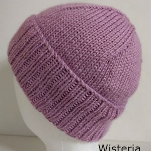 May include: A purple knitted beanie hat with a folded brim. The hat is made with a simple stitch pattern and has a soft, cozy feel.