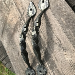 Peut inclure: Deux poignées de porte en métal noir avec un design torsadé et une extrémité pointue martelée.