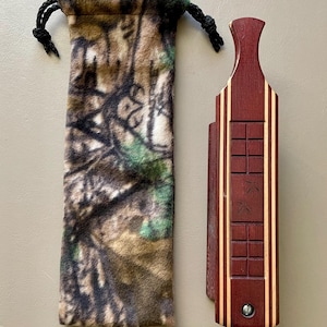 May include: A wooden, red and cream colored, hand-carved,  call with a camouflage fabric pouch. The call has a small screw on the bottom.