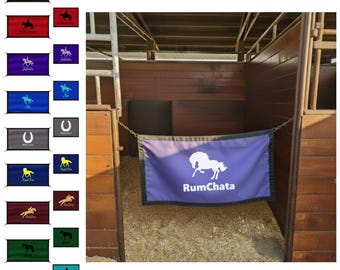 May include: A variety of horse stall signs in different colors, each featuring a horse-related design. The signs include names like "RumChata," "Bailey," and "Juliet." The signs are rectangular and made of fabric.