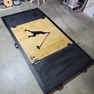 May include: A black and wood folding platform with a silhouette of a person holding a microphone. The platform has black metal hinges and handles. The platform is labeled "LEGENDARY FITNESS".