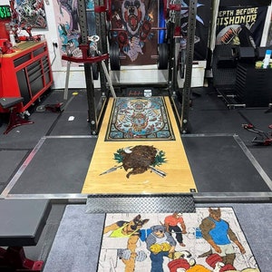 May include: A gray and black weightlifting mat with the text "BUFF WORKOUT" printed on it. The mat features a cartoon illustration of five dogs lifting weights.