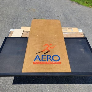 May include: AERO Physical Therapy & Sports Medicine logo on a wooden platform with black metal sides.