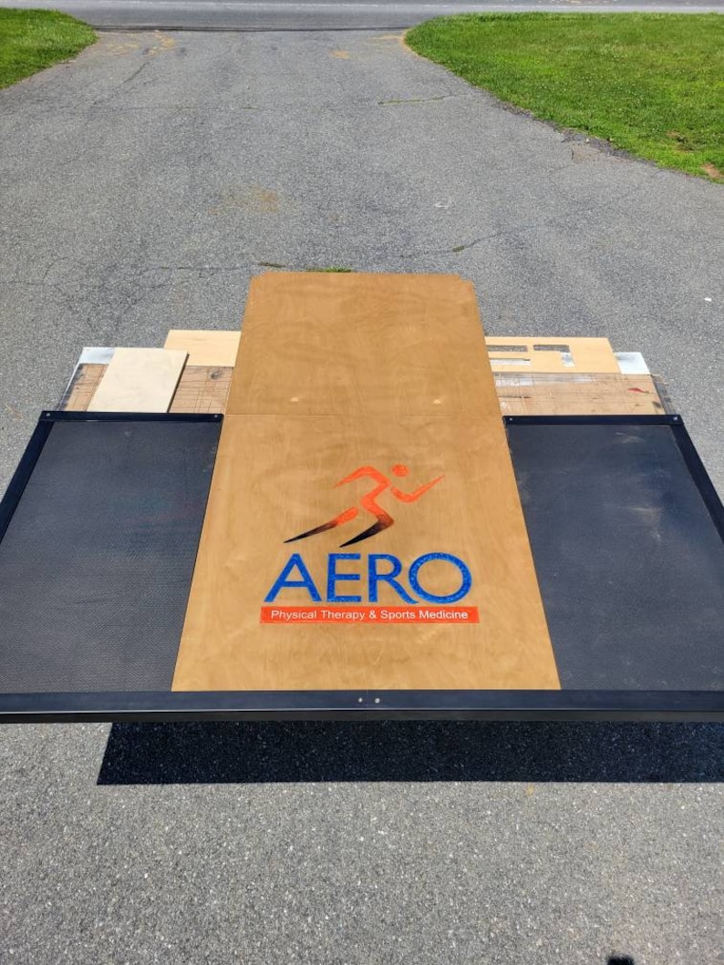 May include: AERO Physical Therapy & Sports Medicine logo on a wooden platform with black metal sides.