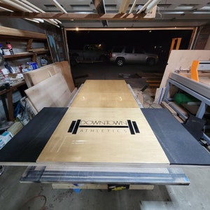 May include: A wooden platform with black padding on the sides. The platform has the text "DOWNTOWN ATHLETICS" printed on it.