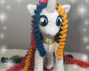 May include: White crocheted unicorn with a long, colorful, curly mane and tail. The mane is pink, blue, yellow, and green. The tail is red, yellow, brown, and green.