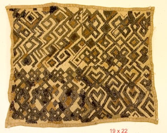 May include: A beige textile with a geometric pattern in brown and black. The textile has a fringe border. 19 x 22.