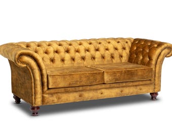 May include: A gold velvet tufted sofa with wooden legs. The sofa has a classic design with a high back and rolled arms.