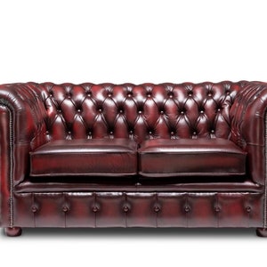 May include: A deep red leather chesterfield sofa with button tufting and rolled arms. The sofa has a classic design and is perfect for a traditional living room.