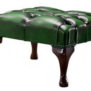May include: A green leather ottoman with a tufted top and four wooden legs.