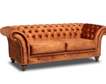 May include: A brown velvet tufted sofa with wooden legs. The sofa has a classic design with a high back and rolled arms.