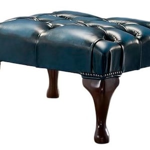 May include: A dark blue leather ottoman with a tufted top and four wooden legs.