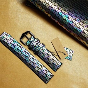 May include: Two iridescent watch straps with a scale pattern. The straps are black with a rainbow sheen. One strap is longer and has a buckle. The other strap is shorter and does not have a buckle.
