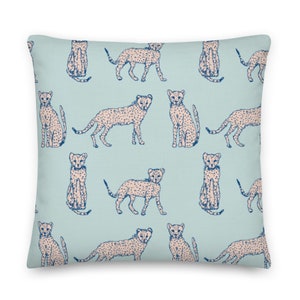 May include: A light blue throw pillow with a repeating pattern of cheetah print animals in a light pink color. The cheetah print is outlined in dark blue.