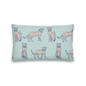 May include: A light blue throw pillow with a repeating pattern of pink cheetahs with blue spots. The cheetahs are in various poses, including sitting, standing, and running.