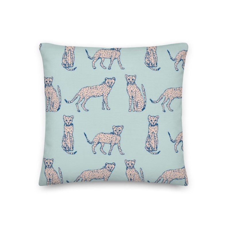 May include: A light blue throw pillow with a repeating pattern of pink and blue cheetahs. The cheetahs are in various poses, including sitting, standing, and running.