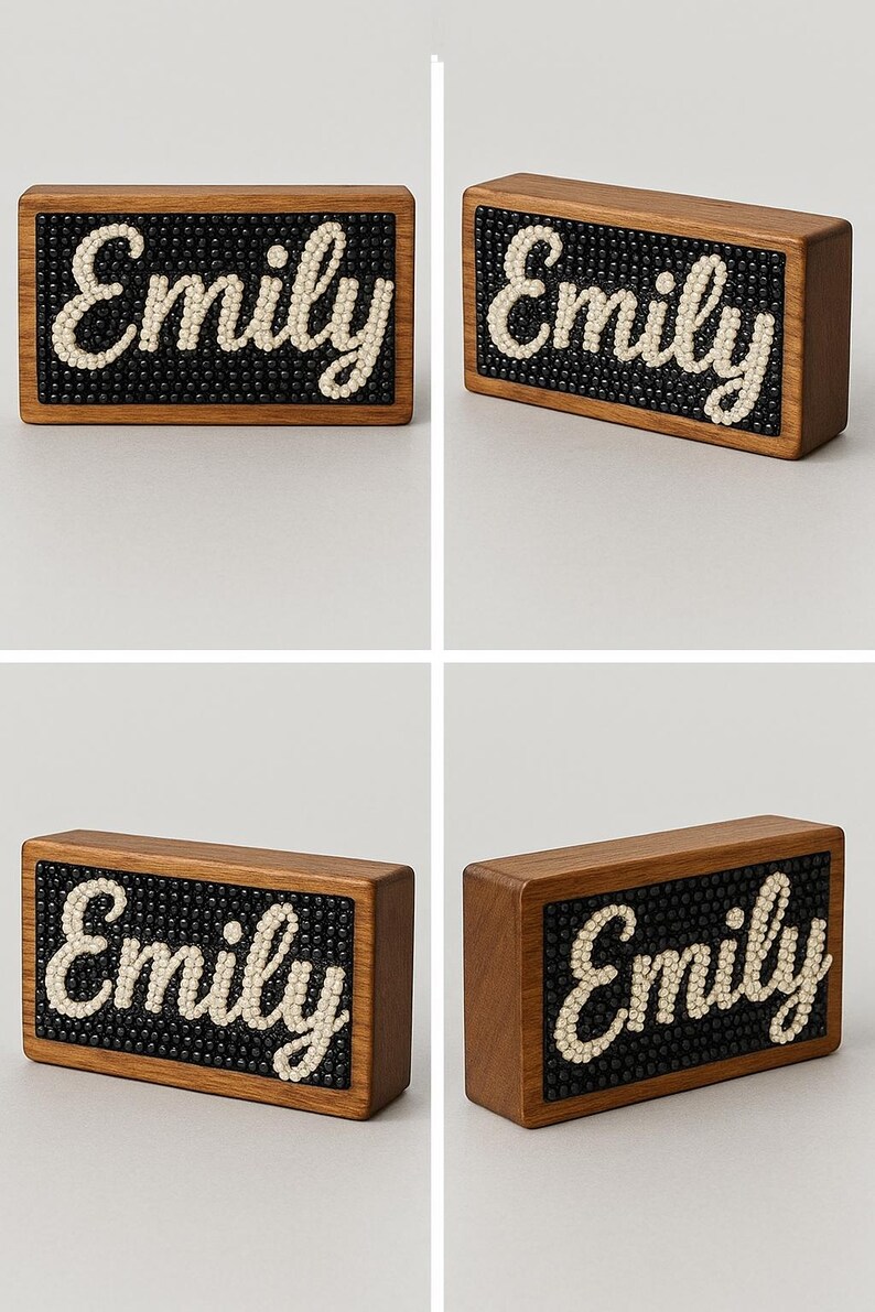 May include: Wooden block sign with the name "Emily" spelled out in cream-colored beads on a black beaded background. The sign is encased in a rectangular, brown wooden frame.