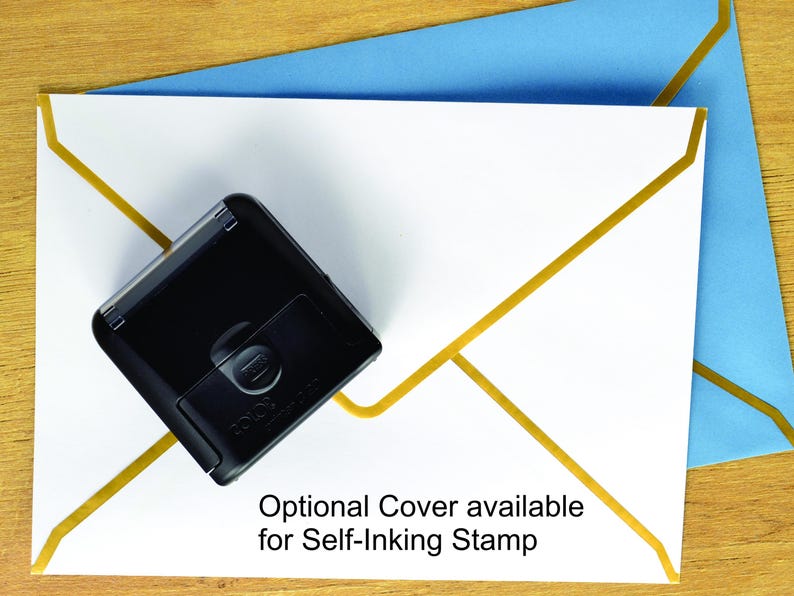 May include: A black self-inking stamp positioned on a white envelope with gold geometric lines, which is placed over a light blue envelope. The text on the white envelope reads: Optional Cover available for Self-Inking Stamp.