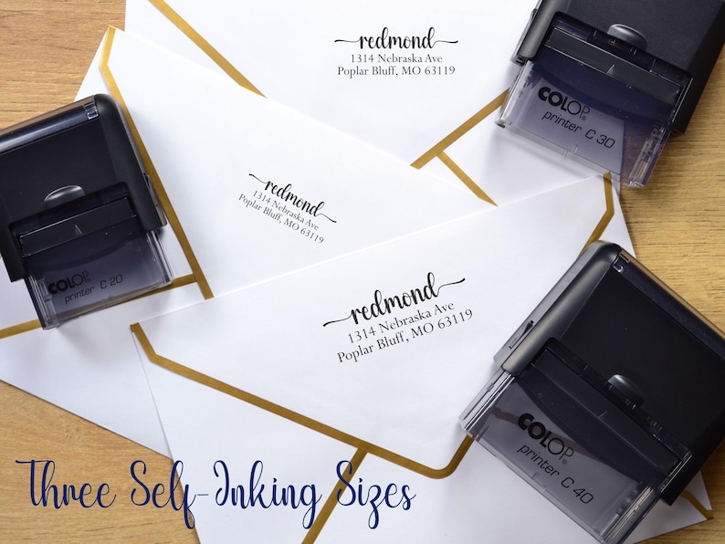 May include: Three black self-inking stamps labeled Colop Printer C 20, C 30, and C 40, positioned next to white envelopes with gold geometric borders. Each envelope features the printed address: redmond, 1314 Nebraska Ave, Poplar Bluff, MO 63119.