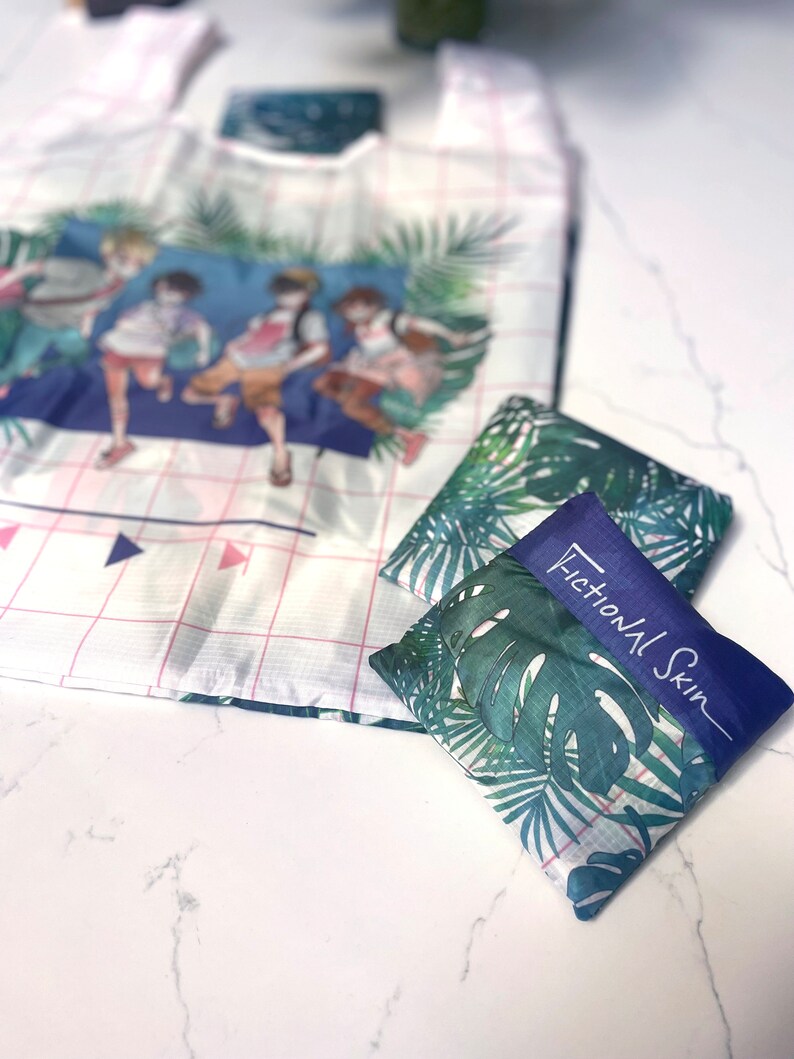 May include: A white and pink reusable shopping bag with a tropical print featuring four cartoon figures. The bag is folded and placed on a white marble surface. The bag is labelled "Fictional Skin".