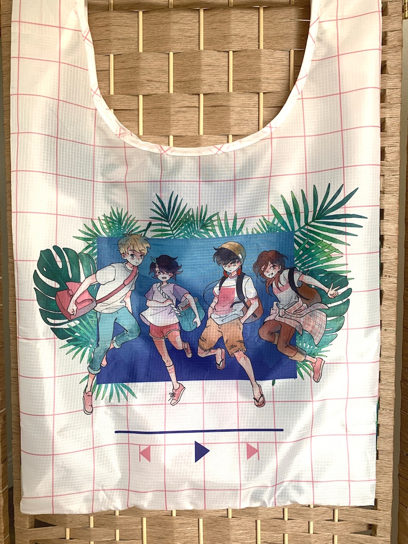 May include: White reusable tote bag with a pink grid pattern. The bag features a colourful illustration of four cartoon characters running through a tropical scene with palm trees and a blue background. The text "PLAY" is printed in white at the bottom of the bag.