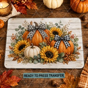 May include: A rectangular sublimation transfer sheet featuring a rustic white wood background with two orange pumpkins and one white pumpkin, decorated with yellow sunflowers, green eucalyptus leaves, and bows in leopard print and black and white plaid.